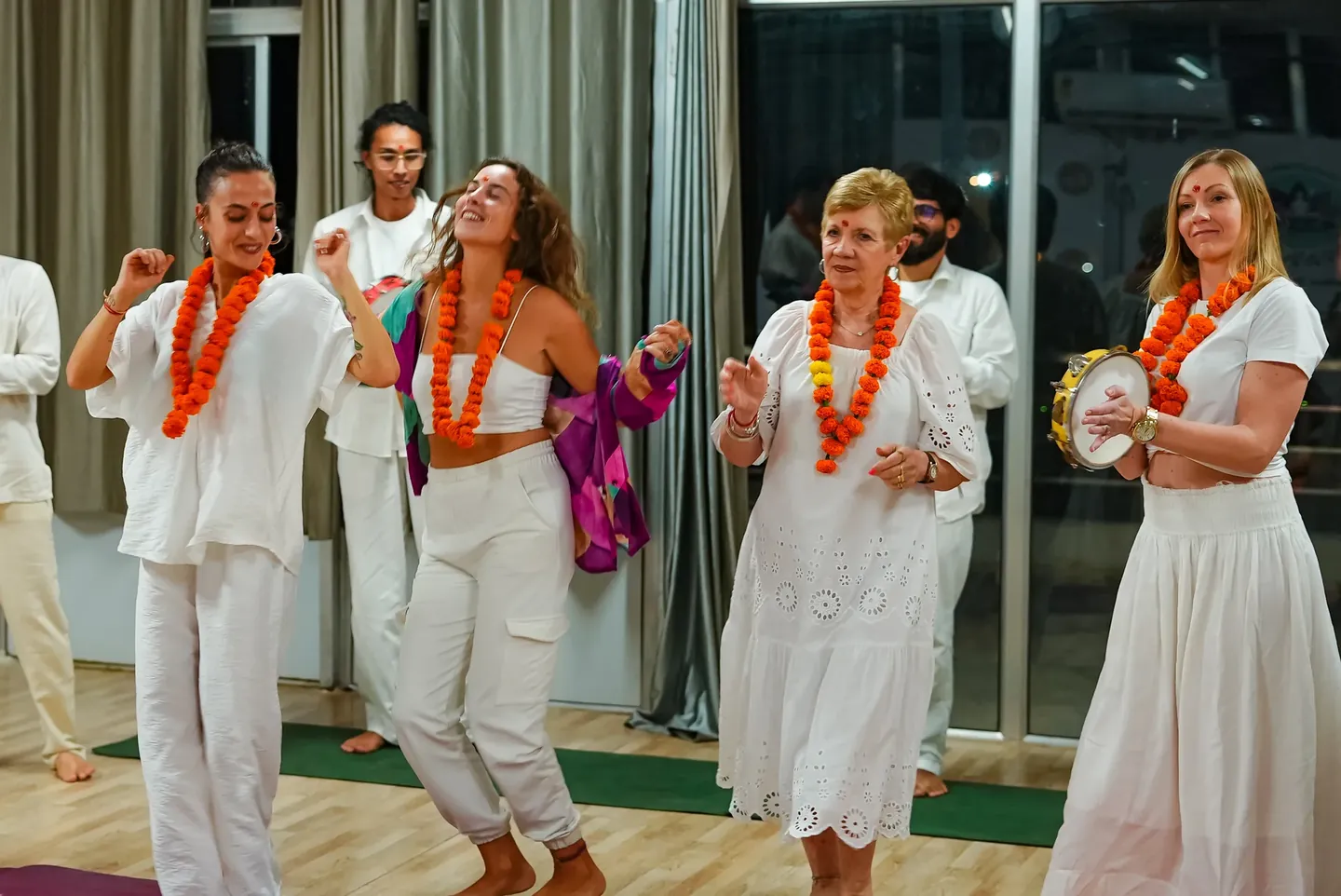 Participants wearing flower garlands and celebrating indoors