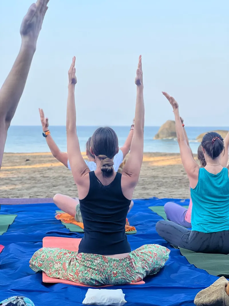 Seated yoga practice with arms raised beside the sea