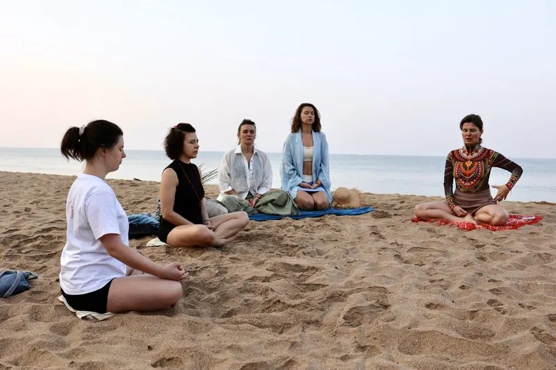 A group sitting in quiet meditation on the Goa beach