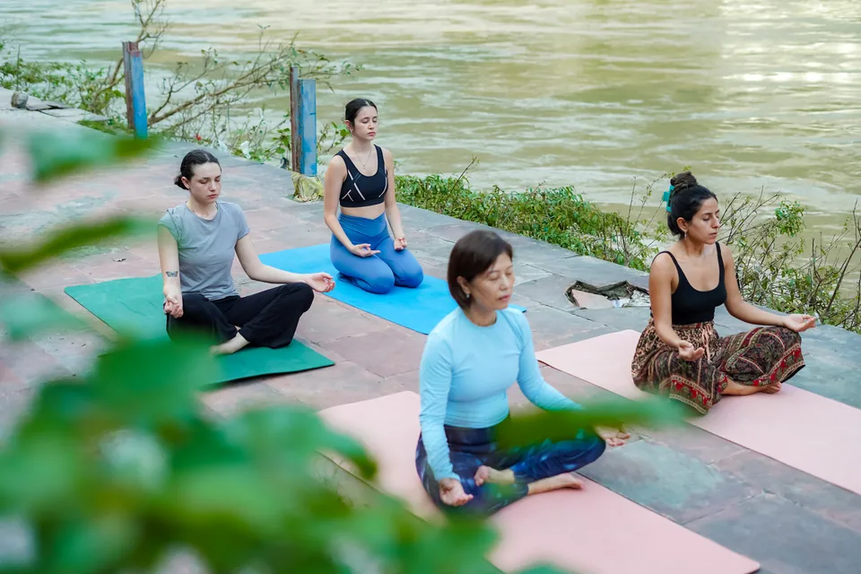 Four participants sitting in meditation beside the Ganges in Rishikesh